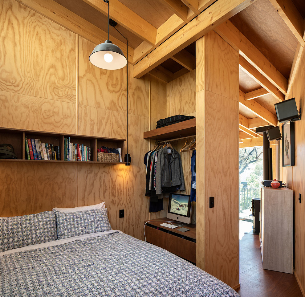 Uriges Schlafzimmer mit brauner Wandfarbe, dunklem Holzboden und braunem Boden in Dunedin