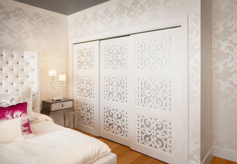 Cette photo montre une grande chambre tendance avec un mur blanc et un sol en bois brun.
