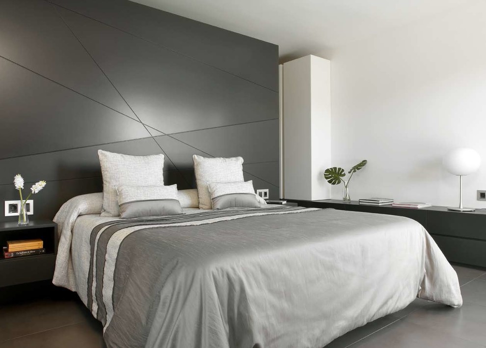 Modelo de dormitorio principal actual de tamaño medio con suelo de cemento, paredes blancas y suelo gris