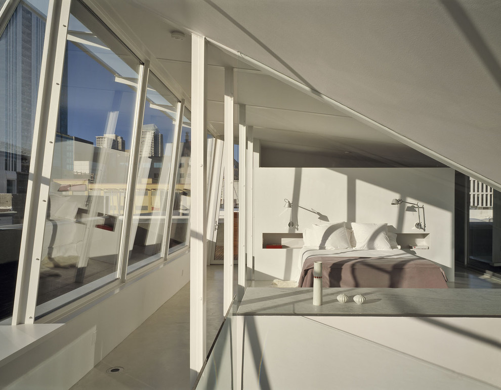 Modelo de dormitorio principal industrial de tamaño medio con paredes blancas, suelo de cemento y suelo gris