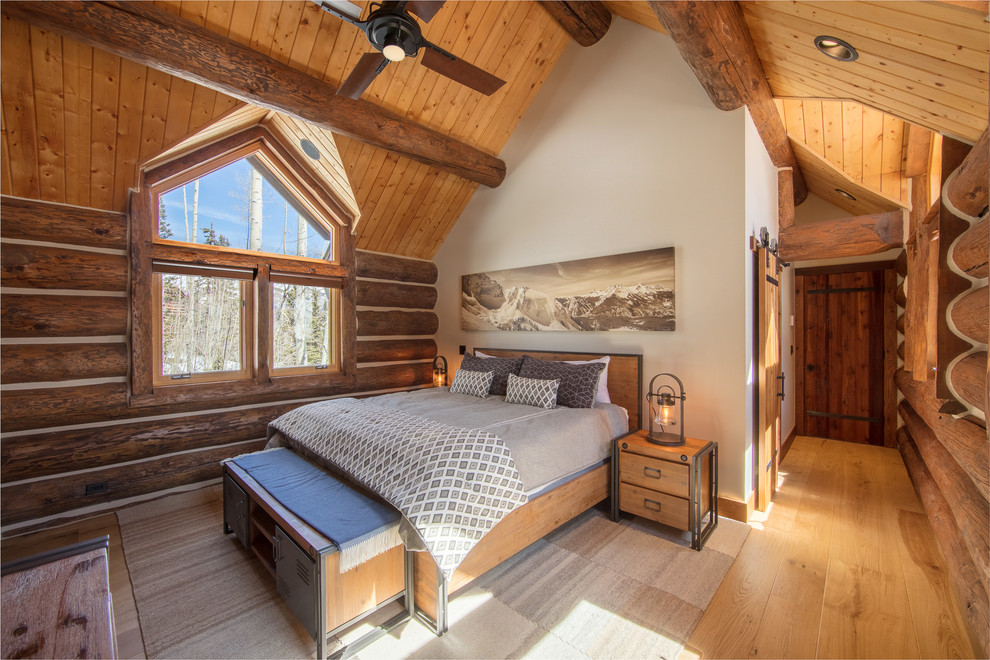 Ejemplo de dormitorio principal rural con paredes blancas, suelo de madera en tonos medios y suelo marrón