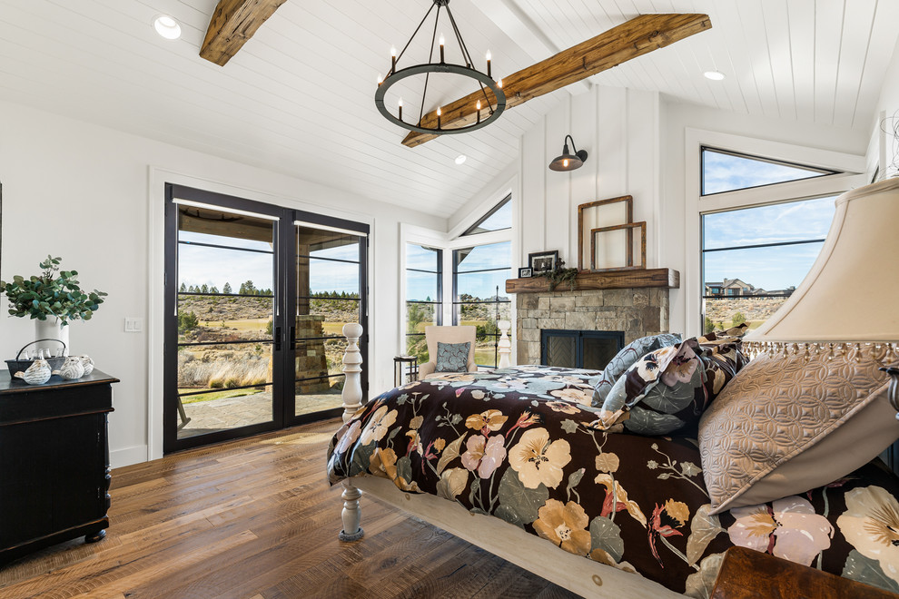 Mid-sized farmhouse master medium tone wood floor and brown floor bedroom photo in Other with white walls, a standard fireplace and a stone fireplace