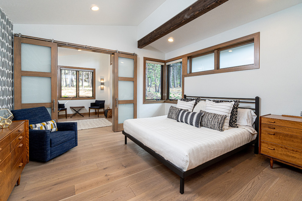 Modelo de dormitorio principal rústico de tamaño medio sin chimenea con paredes blancas, suelo de madera clara y suelo beige