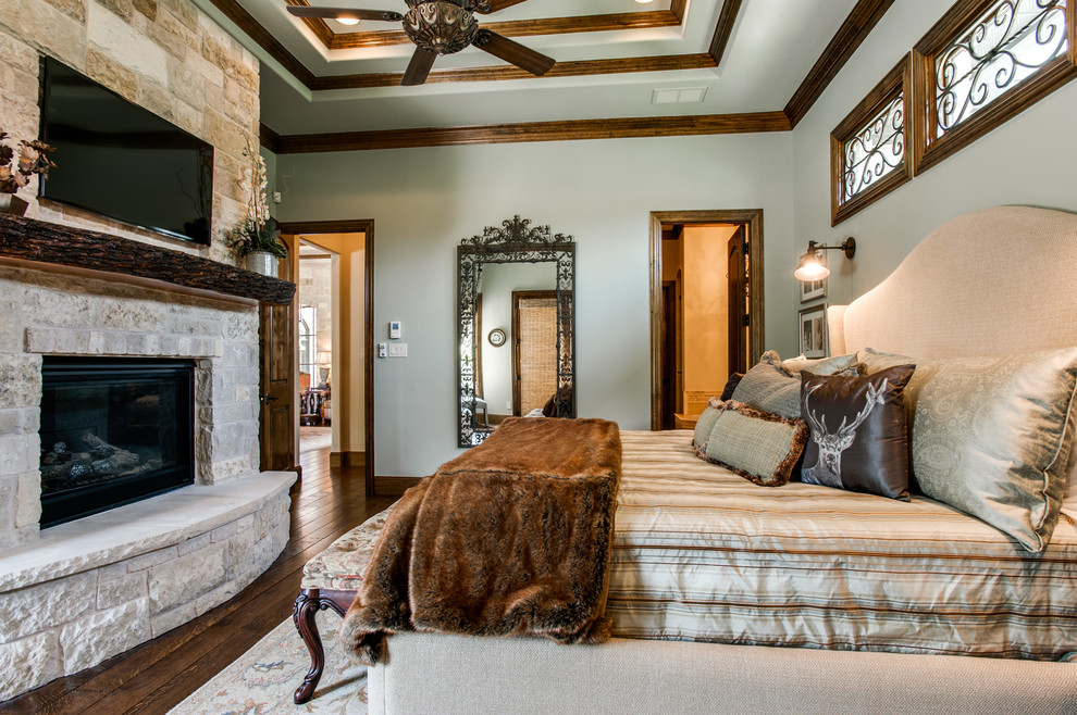 Klassisches Hauptschlafzimmer mit grüner Wandfarbe, braunem Holzboden, Kamin und Kaminumrandung aus Stein in Dallas