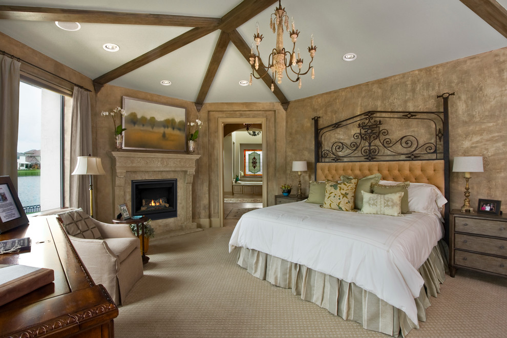 На фото: большая хозяйская спальня в классическом стиле с ковровым покрытием, коричневыми стенами и угловым камином