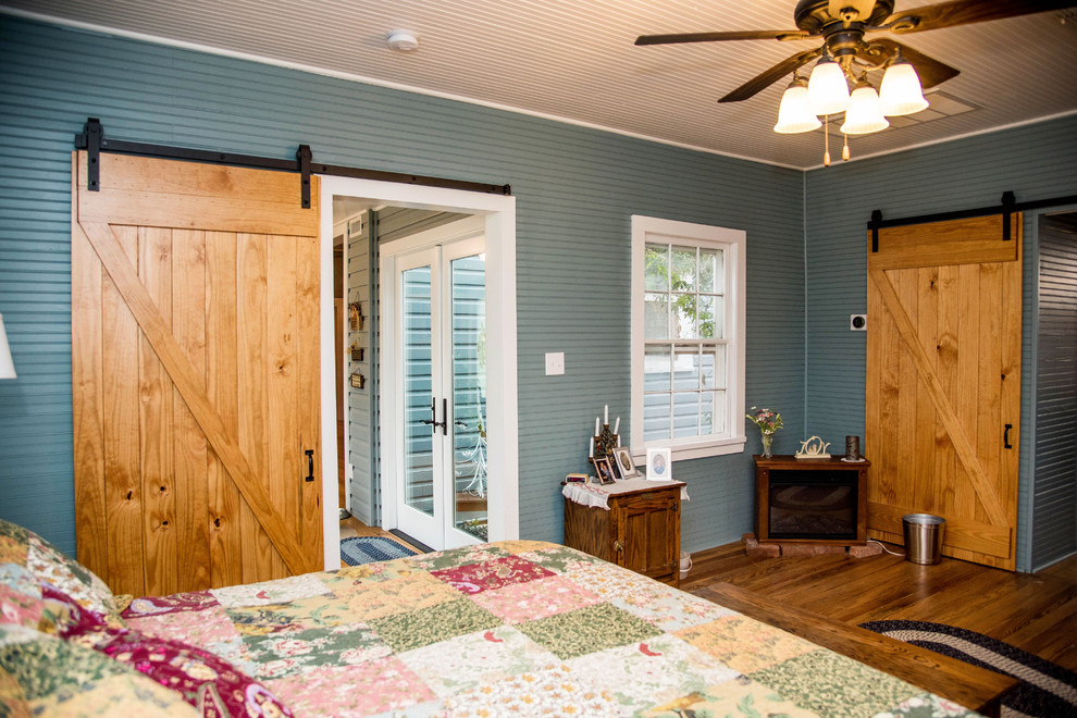Aménagement d'une chambre parentale campagne de taille moyenne avec un mur bleu, parquet foncé et un sol marron.