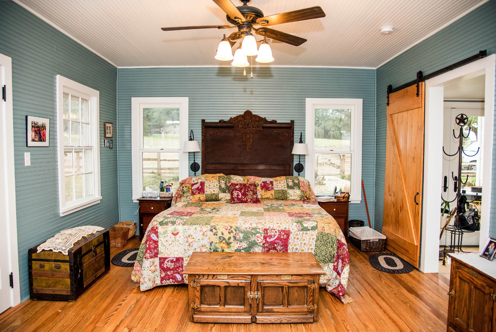Cette photo montre une chambre parentale nature de taille moyenne avec un mur bleu, parquet foncé et un sol marron.