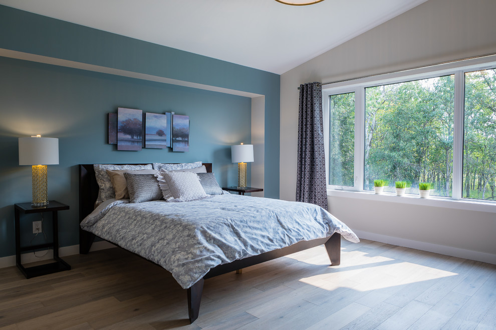 На фото: большая хозяйская спальня в классическом стиле с синими стенами и полом из ламината с