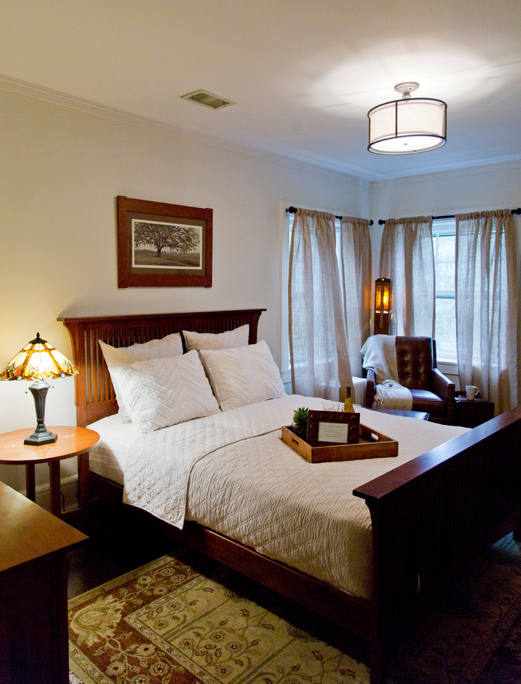 Cette image montre une chambre d'amis craftsman de taille moyenne avec un mur beige, parquet foncé et un sol marron.