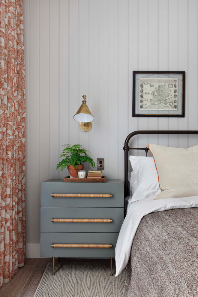 Modelo de dormitorio principal tradicional renovado de tamaño medio con paredes grises, suelo de madera en tonos medios, suelo marrón y panelado