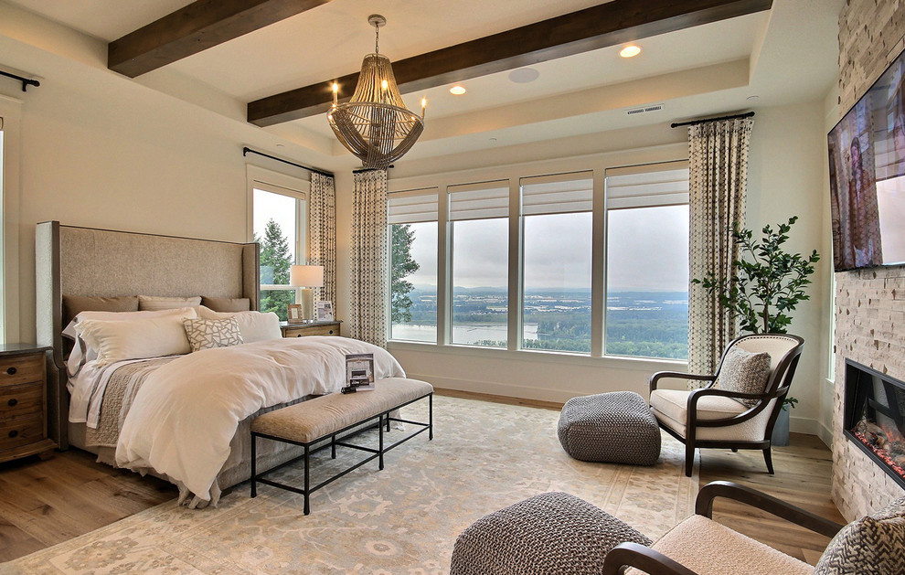Geräumiges Country Hauptschlafzimmer mit beiger Wandfarbe, hellem Holzboden, Kamin, Kaminumrandung aus Stein und braunem Boden in Portland