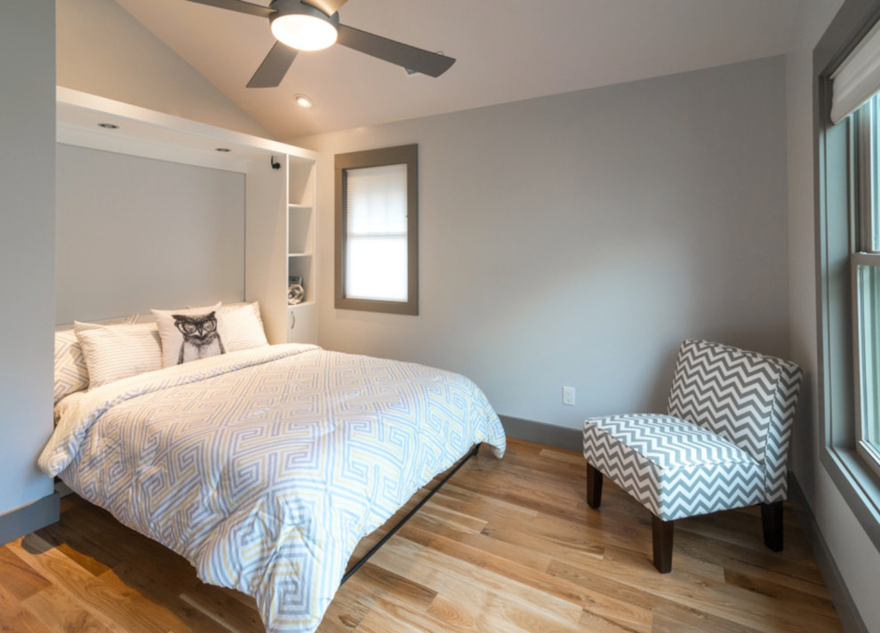 Modelo de habitación de invitados de estilo americano de tamaño medio con paredes grises y suelo de madera clara