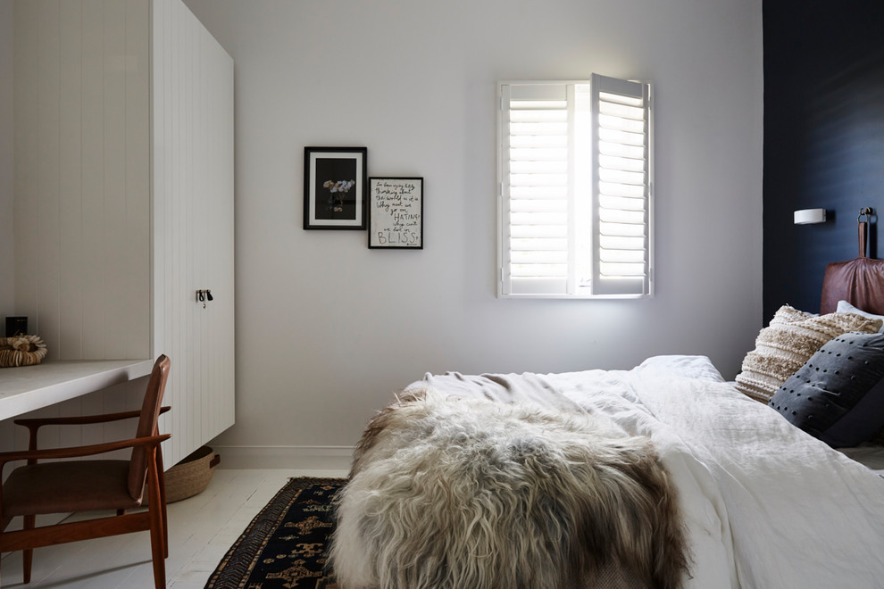 This is an example of a world-inspired guest bedroom in Sydney with blue walls, painted wood flooring and white floors.