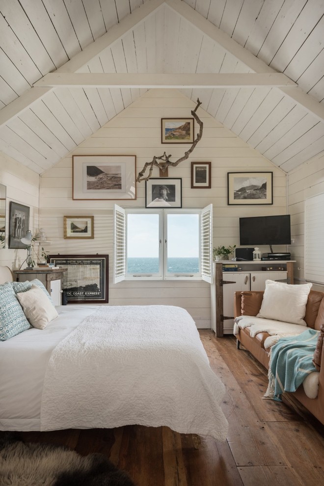 コーンウォールにあるビーチスタイルのおしゃれな主寝室 (白い壁、濃色無垢フローリング、茶色い床)