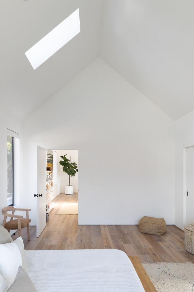 Kleines Modernes Hauptschlafzimmer ohne Kamin mit weißer Wandfarbe, braunem Boden, gewölbter Decke und braunem Holzboden in Los Angeles