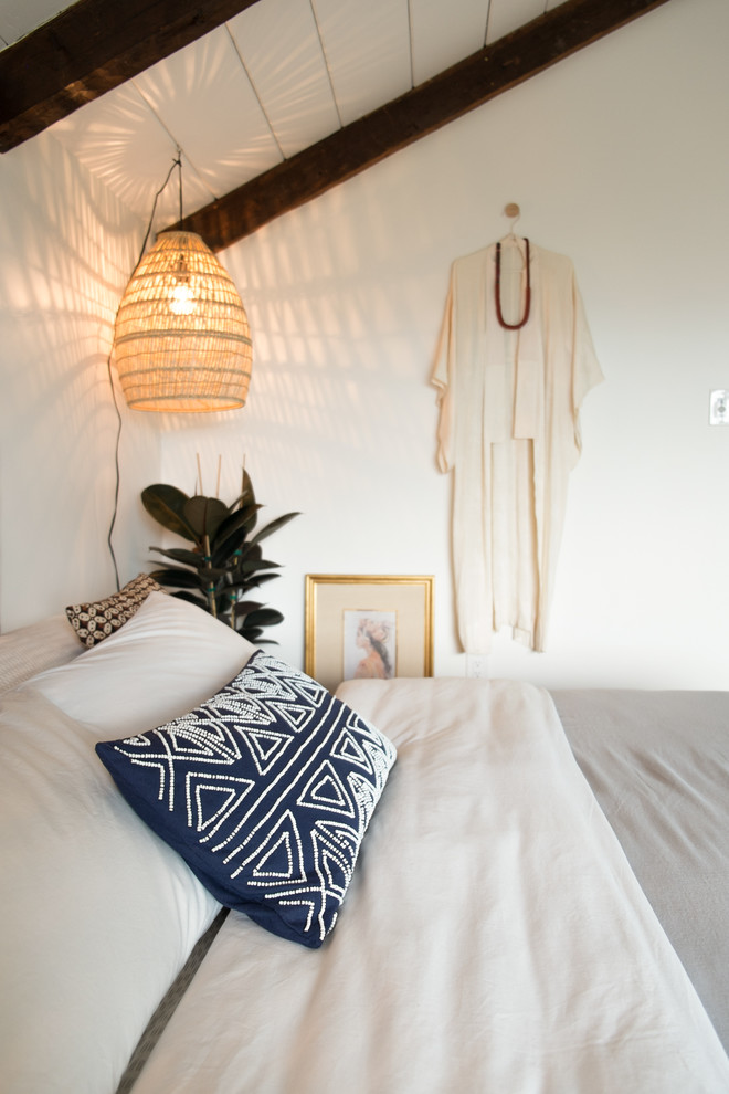 This is an example of a large bohemian master bedroom in San Francisco with white walls, light hardwood flooring and a standard fireplace.