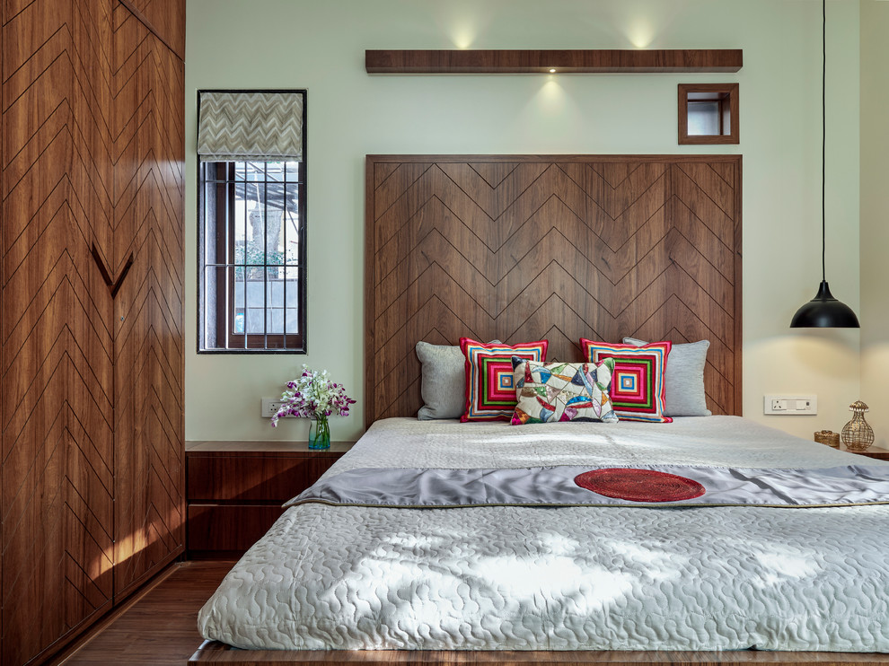 Immagine di una camera da letto design con pareti verdi, parquet scuro e pavimento marrone