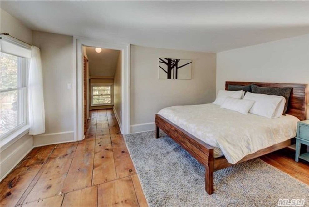 Imagen de dormitorio principal actual de tamaño medio con paredes blancas y suelo de madera en tonos medios
