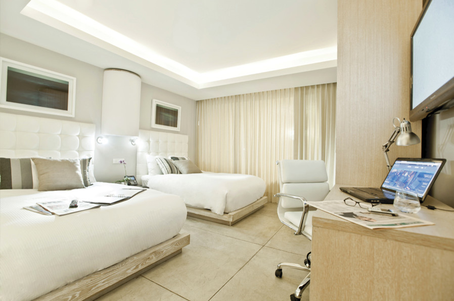 Diseño de dormitorio tipo loft moderno grande sin chimenea con paredes beige, suelo de baldosas de cerámica y suelo beige
