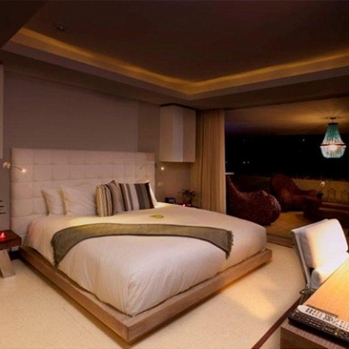 Ejemplo de dormitorio tipo loft moderno grande sin chimenea con paredes beige, suelo de baldosas de cerámica y suelo beige
