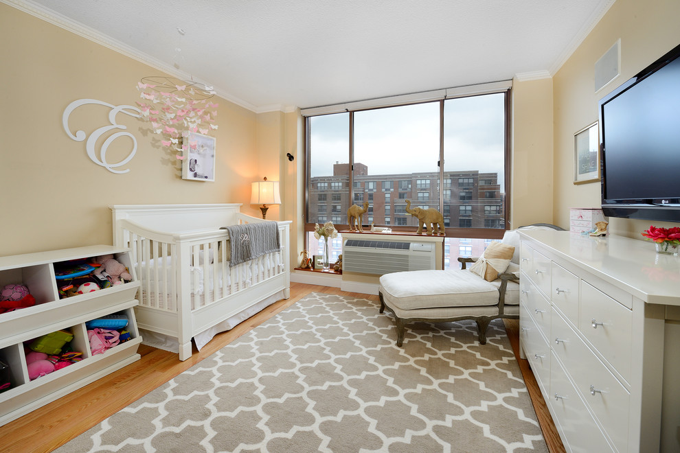 Exemple d'une chambre de bébé tendance avec un mur jaune et parquet clair.