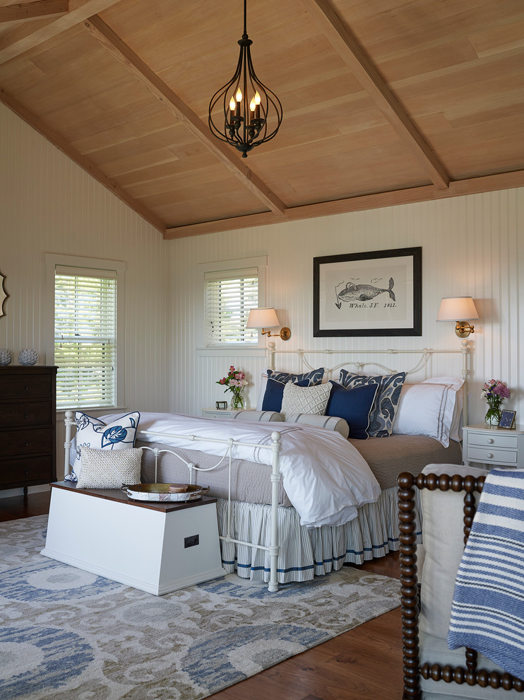 Aménagement d'une chambre parentale bord de mer avec un mur blanc et un sol en bois brun.