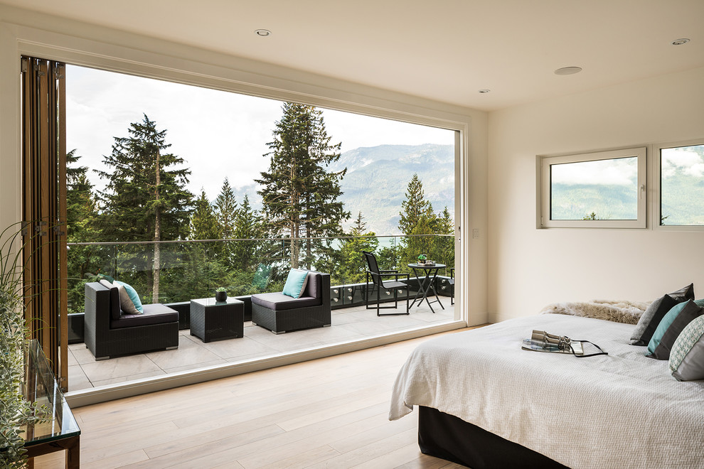 Photo of an expansive contemporary master bedroom in Vancouver with white walls, medium hardwood flooring, brown floors and no fireplace.
