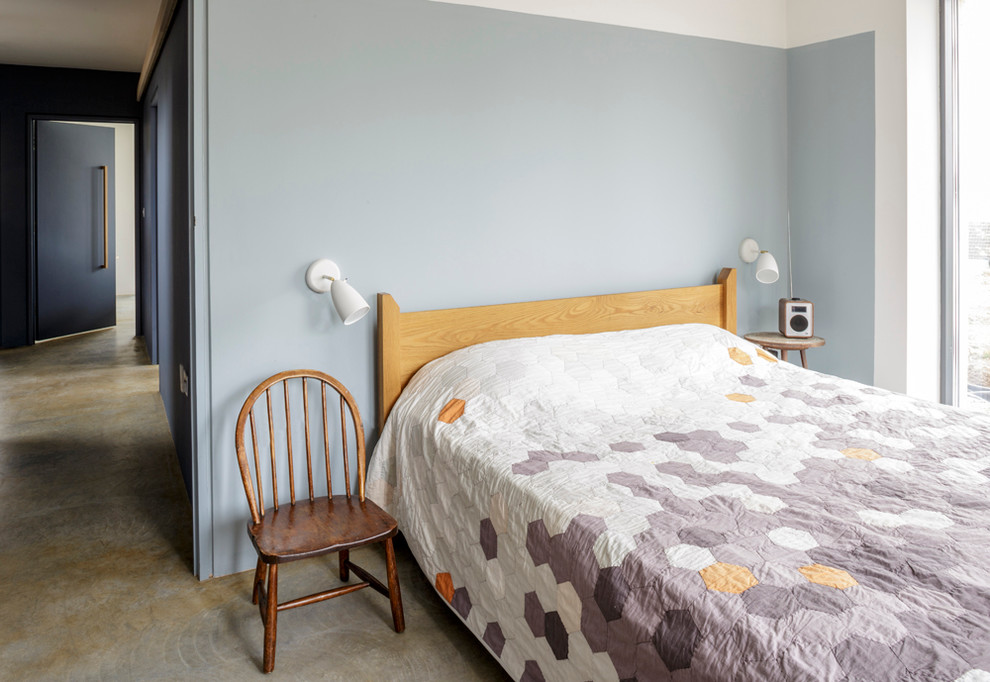 На фото: хозяйская спальня среднего размера в стиле модернизм с синими стенами и бетонным полом с