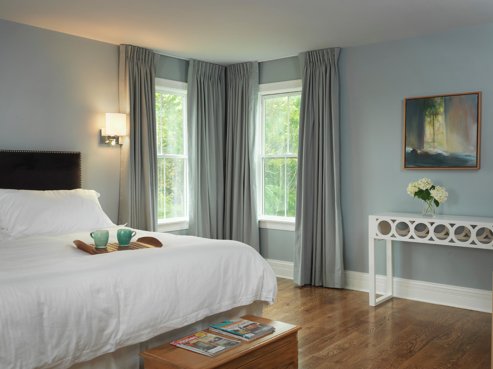Modelo de dormitorio principal campestre con paredes azules y suelo de madera en tonos medios