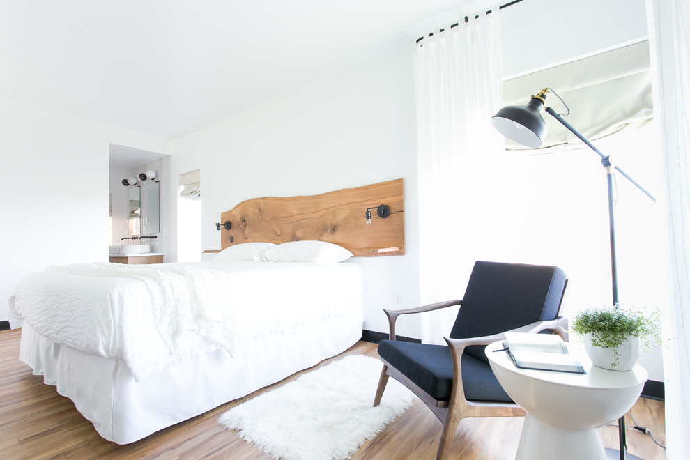 Cette photo montre une grande chambre d'amis moderne avec un mur blanc, parquet clair et cheminée suspendue.