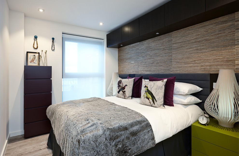 Cette photo montre une petite chambre tendance avec un sol en bois brun et un mur blanc.
