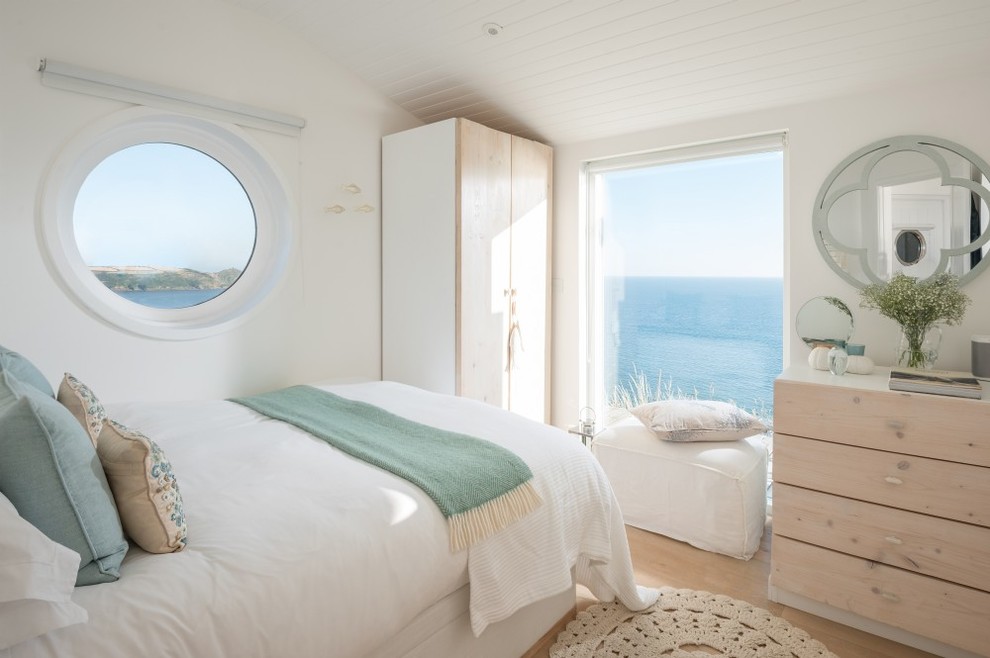 Photo of a small beach style master bedroom in Cornwall with white walls, light hardwood flooring and beige floors.