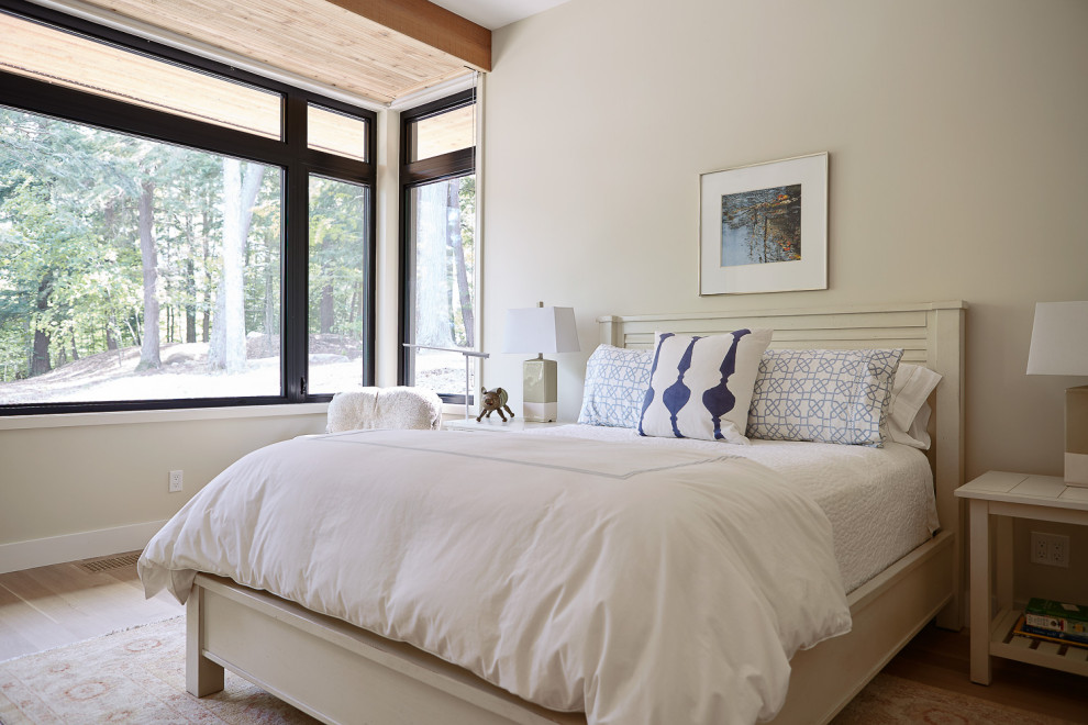 Modelo de habitación de invitados contemporánea de tamaño medio con paredes blancas, suelo de madera clara y suelo marrón