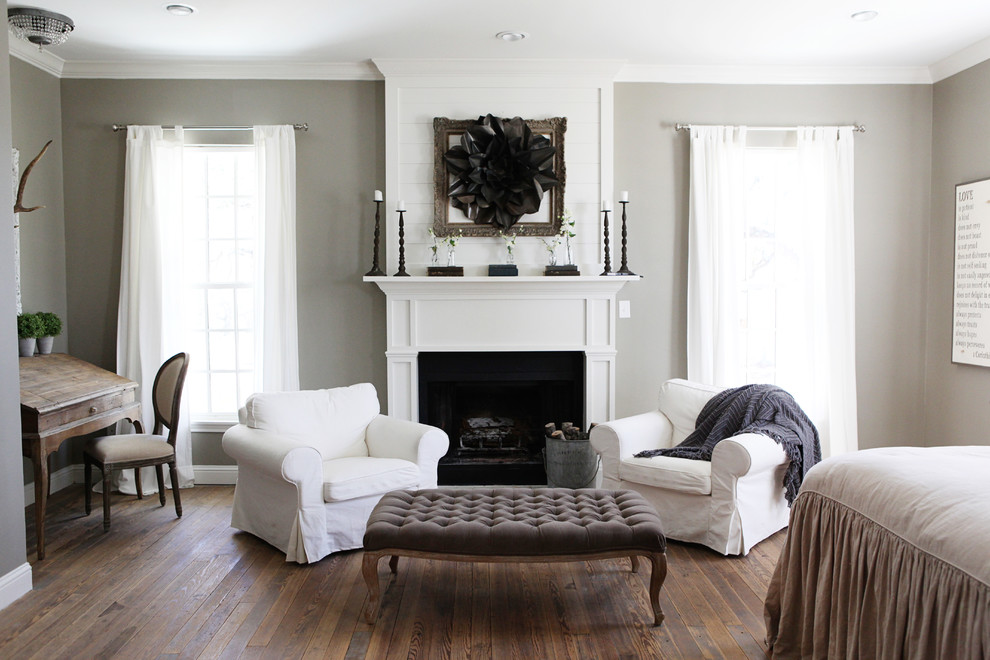 Mittelgroßes Landhausstil Hauptschlafzimmer mit grauer Wandfarbe, braunem Holzboden, Kamin, Kaminumrandung aus Holz und braunem Boden in Austin