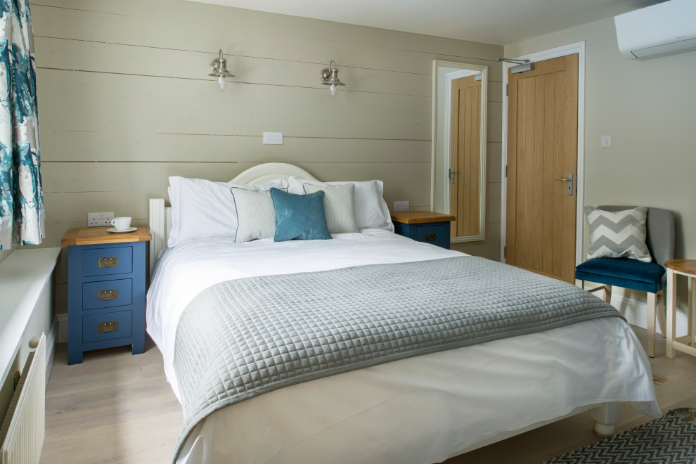 Mittelgroßes Maritimes Gästezimmer mit beiger Wandfarbe, hellem Holzboden, beigem Boden und Holzdielenwänden in Cornwall