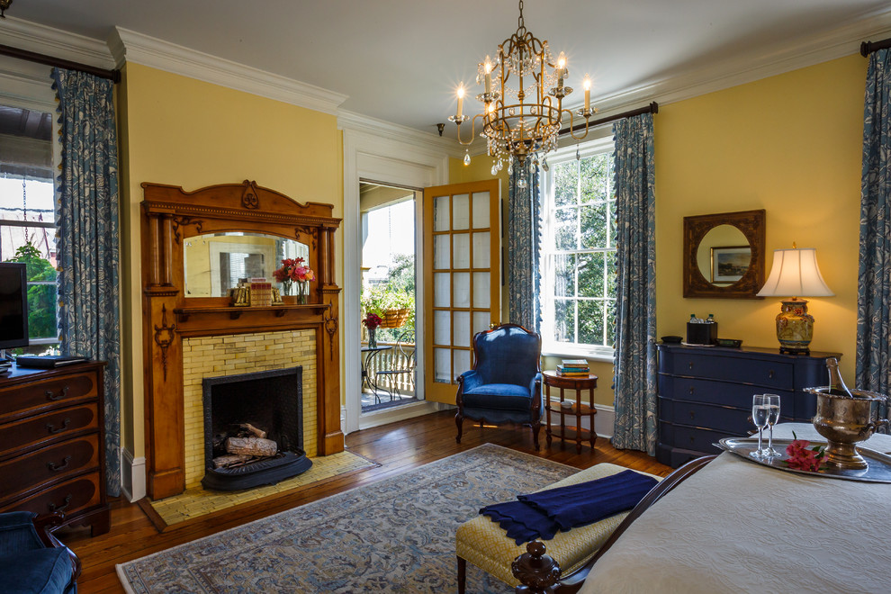 Источник вдохновения для домашнего уюта: большая хозяйская спальня в викторианском стиле с желтыми стенами, темным паркетным полом, стандартным камином и фасадом камина из плитки