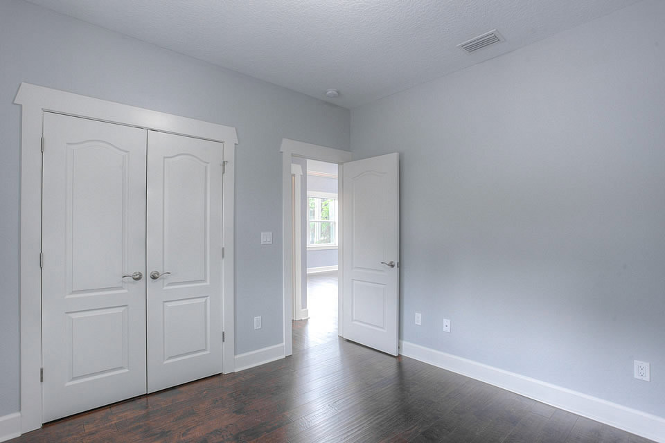 Mid-sized trendy guest dark wood floor and brown floor bedroom photo in Tampa with blue walls and no fireplace