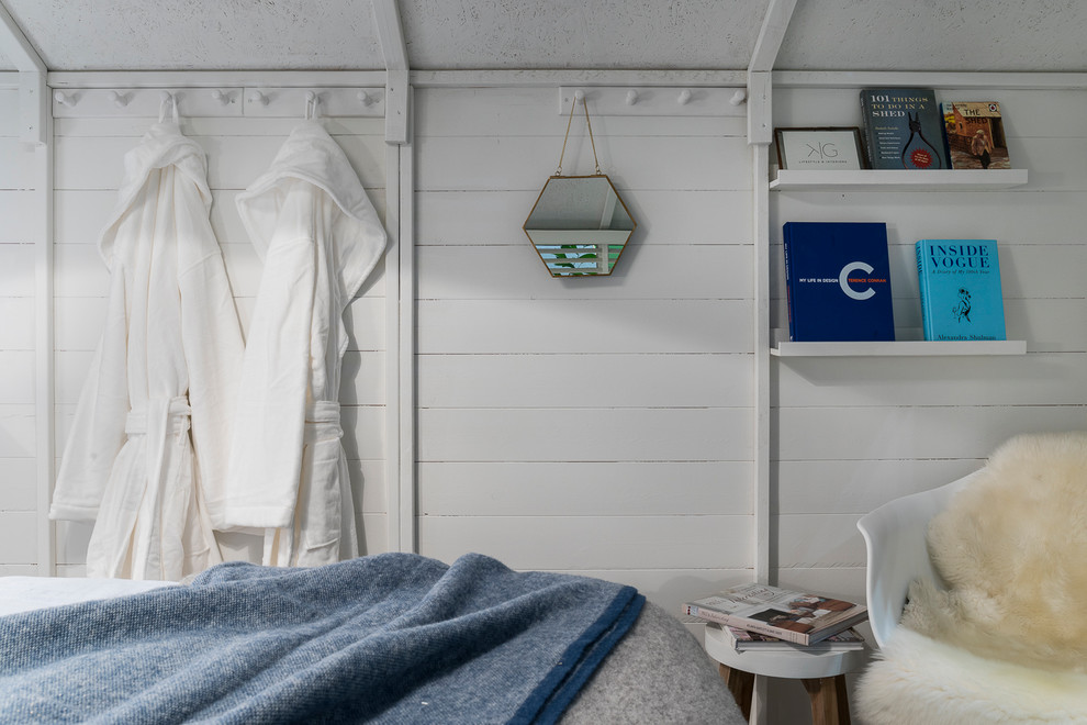 Immagine di una piccola camera degli ospiti scandinava con pareti bianche, pavimento in laminato, stufa a legna e pavimento grigio