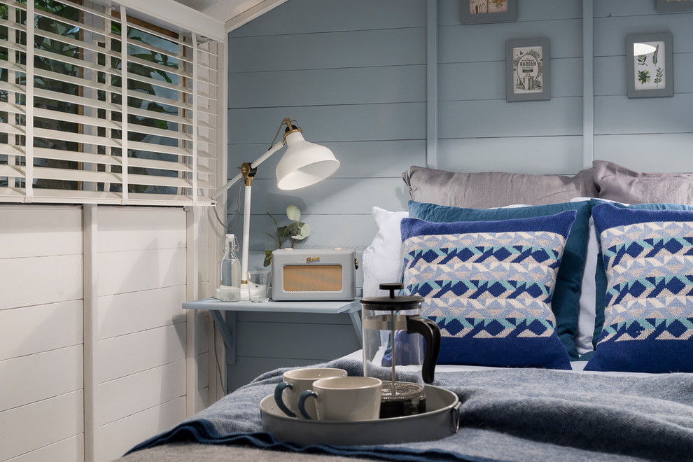 Источник вдохновения для домашнего уюта: маленькая гостевая спальня (комната для гостей) в скандинавском стиле с синими стенами, полом из ламината, печью-буржуйкой и серым полом для на участке и в саду