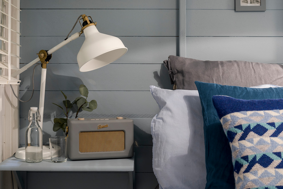 ロンドンにある小さな北欧スタイルのおしゃれな客用寝室 (青い壁、ラミネートの床、薪ストーブ、グレーの床) のインテリア