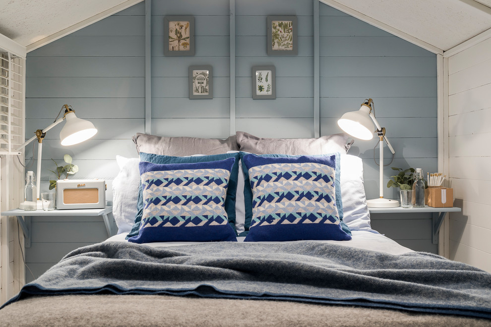 Foto de habitación de invitados escandinava pequeña con paredes azules, suelo laminado, estufa de leña y suelo gris