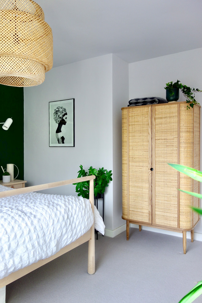 This is an example of a medium sized scandi guest bedroom in Other with green walls, carpet and grey floors.