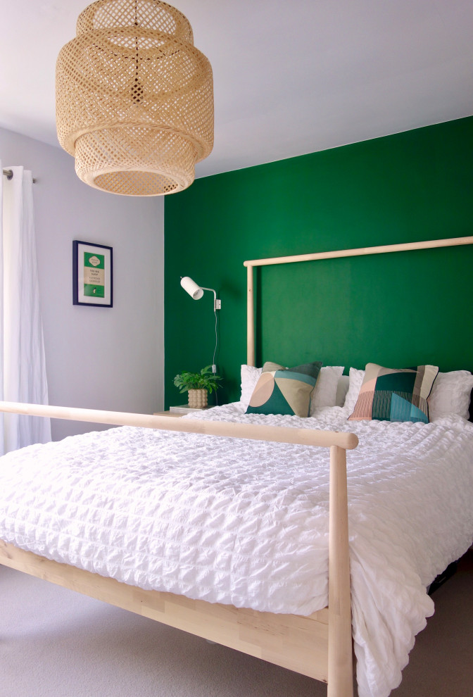 This is an example of a medium sized scandi guest bedroom in Other with green walls, carpet and grey floors.