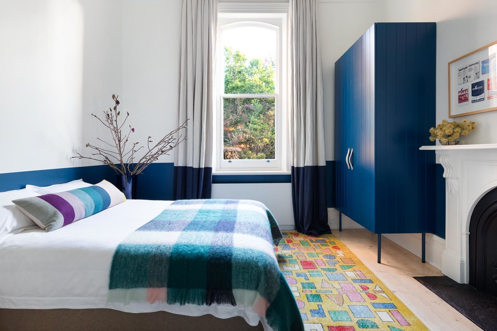Modelo de dormitorio principal tradicional renovado con paredes azules, suelo de madera clara, todas las chimeneas y suelo beige