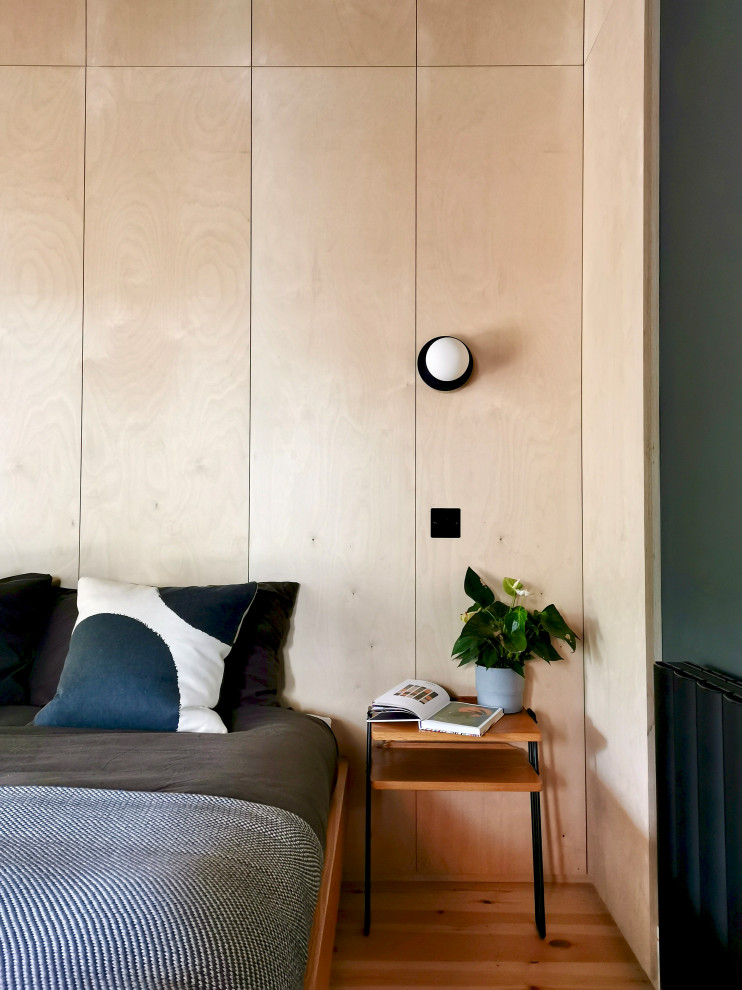 Imagen de dormitorio principal nórdico de tamaño medio sin chimenea con paredes negras, suelo de madera clara y madera