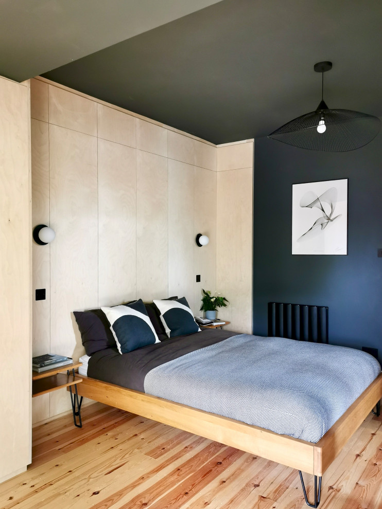 Ejemplo de dormitorio principal escandinavo de tamaño medio sin chimenea con paredes negras, suelo de madera clara y madera
