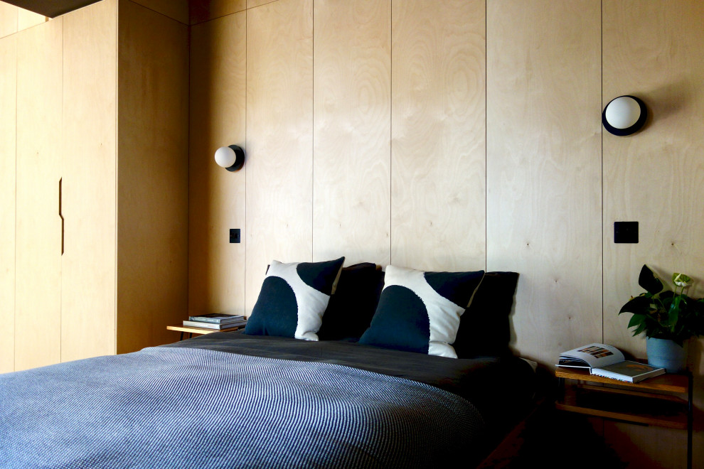 Modelo de dormitorio principal escandinavo de tamaño medio sin chimenea con paredes negras, suelo de madera clara y madera