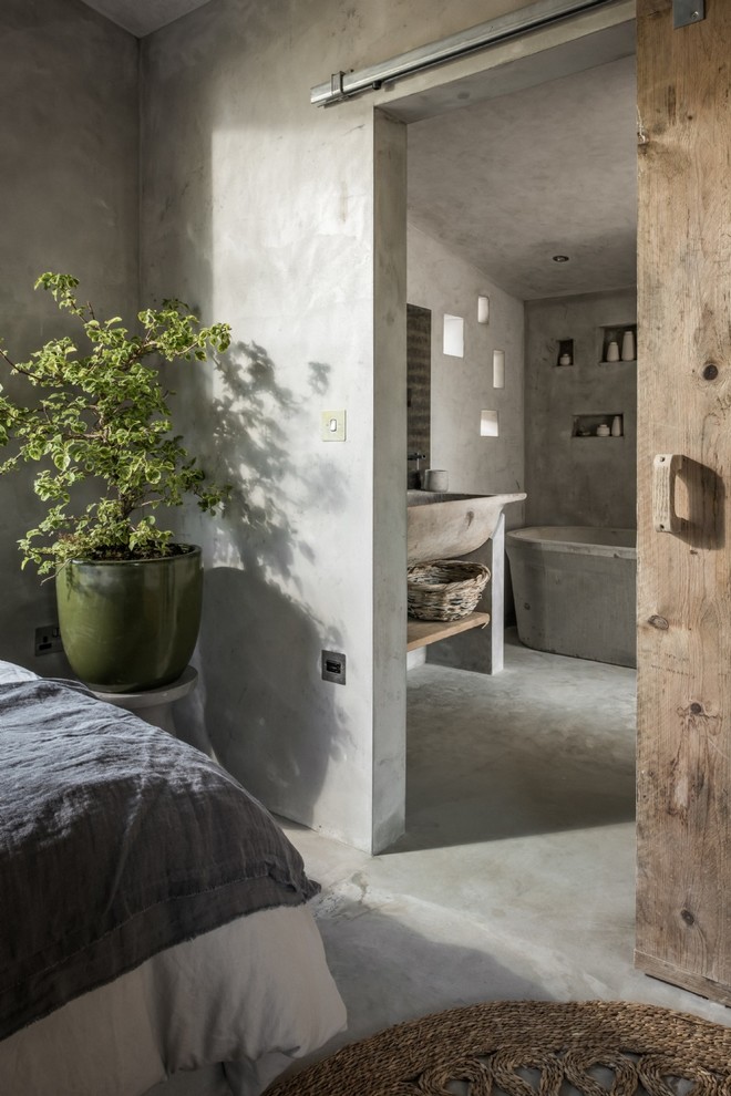 Immagine di una piccola camera matrimoniale stile rurale con pavimento in cemento, pareti beige e pavimento beige