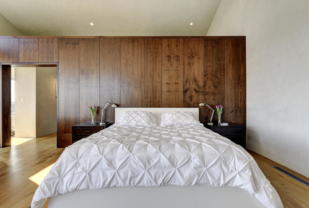 Exemple d'une chambre tendance avec aucune cheminée, un mur blanc et un sol en bois brun.
