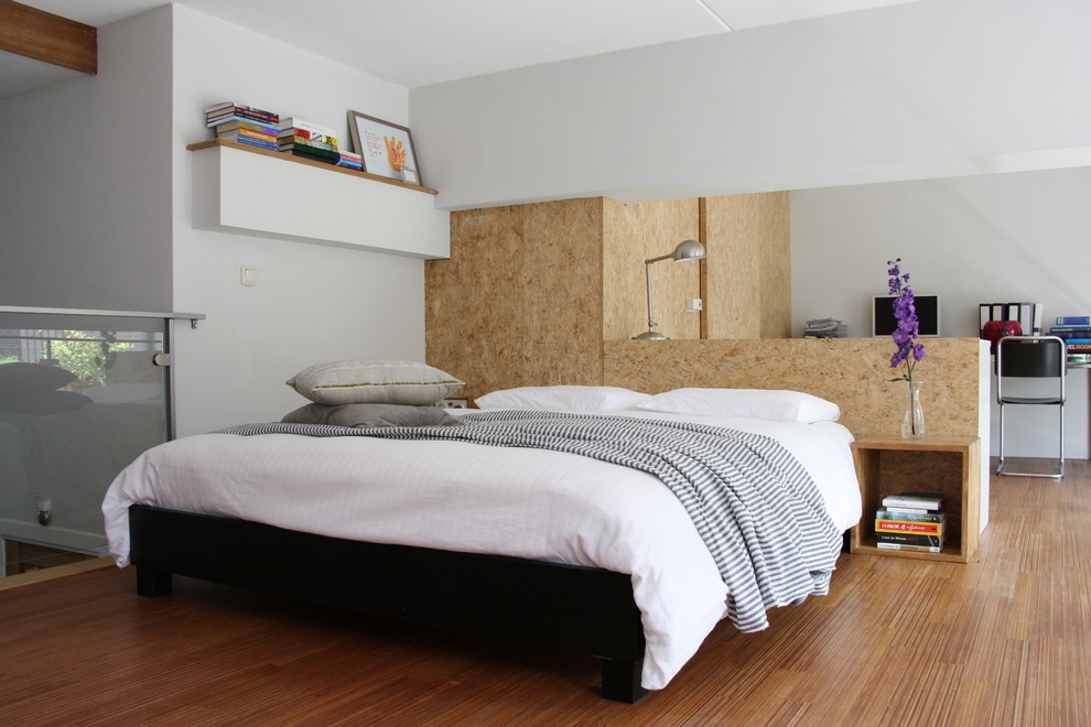 Imagen de dormitorio tipo loft actual sin chimenea con paredes blancas y suelo de madera en tonos medios